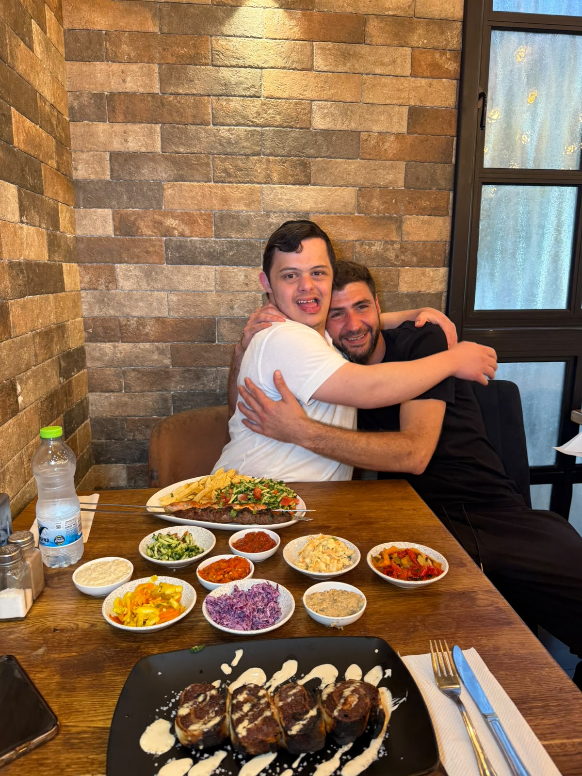 עובדי המסעדה מתחבקים ליד שולחן עמוס במנות ובסלטים